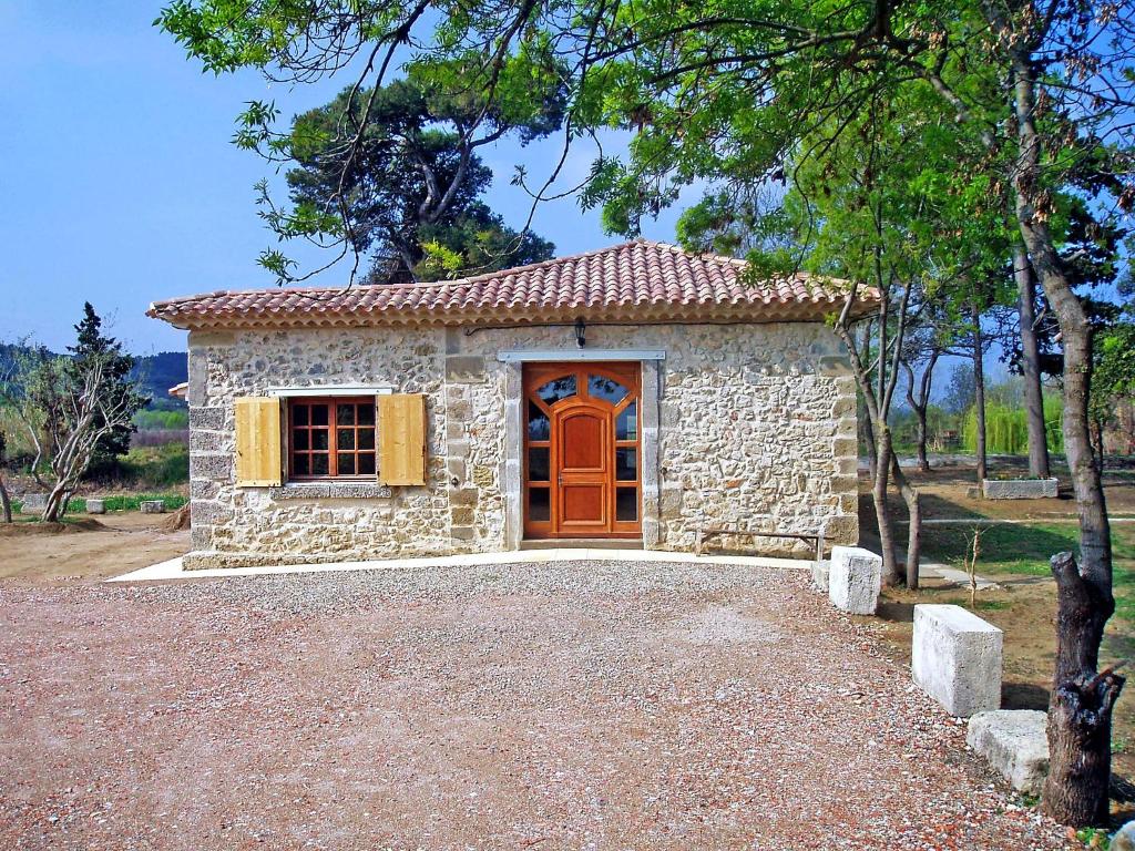 a small stone house with a red door at Holiday Home Domaine La Batisse by Interhome in Lespignan