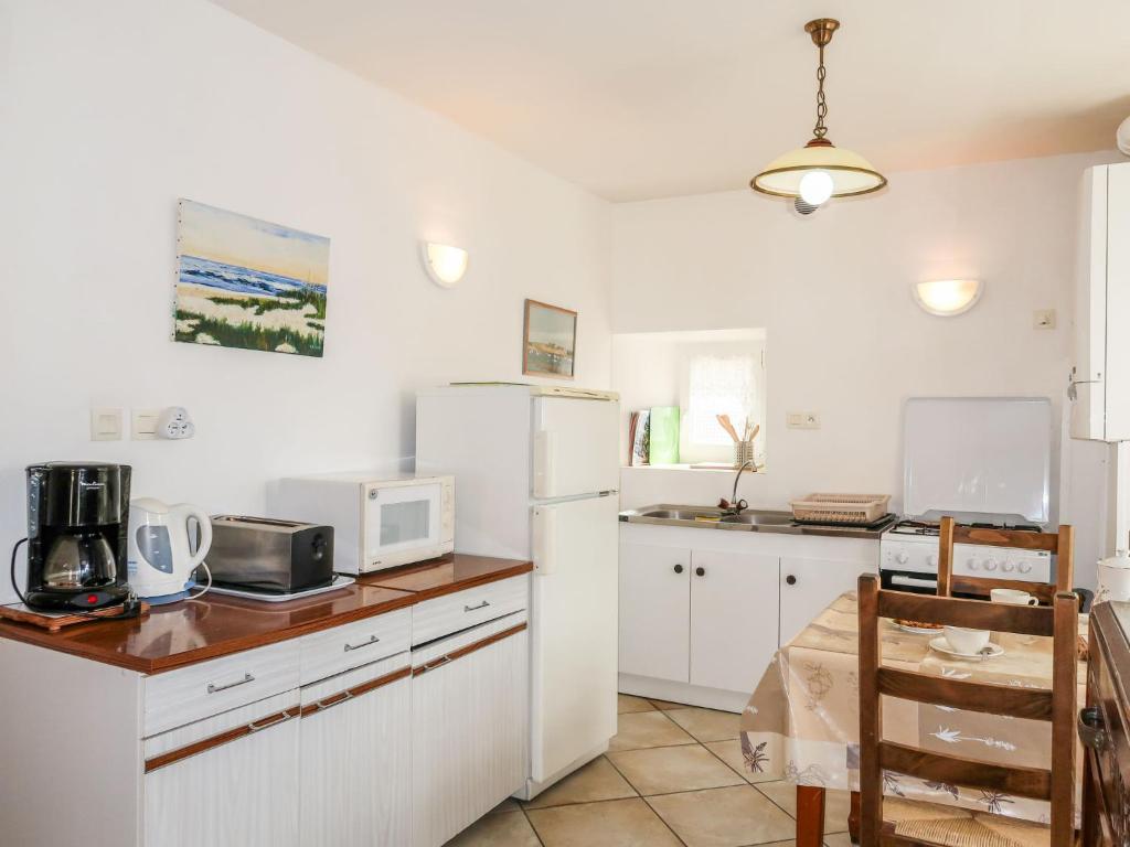 cocina con armarios blancos y nevera blanca en Holiday Home Ty Breiz by Interhome, en Ploemeur