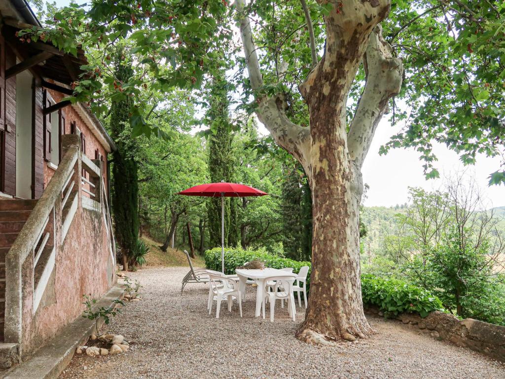 een tafel en stoelen met een rode parasol naast een boom bij Holiday Home L'Amandier - ORN310 by Interhome in Oraison