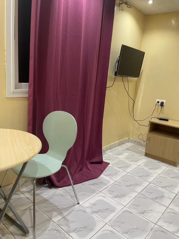 Habitación con cortina púrpura, mesa y silla en Chambre SEJOUR en Dakar