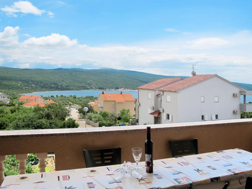 a table with a wine glass on a balcony with a view at Apartment Rosić - KRK218 by Interhome in Kornić