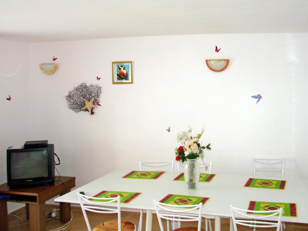 jadalnia z białym stołem z kwiatami i ptakami na ścianie w obiekcie Holiday Home Annemarie by Interhome w mieście Balatonalmádi
