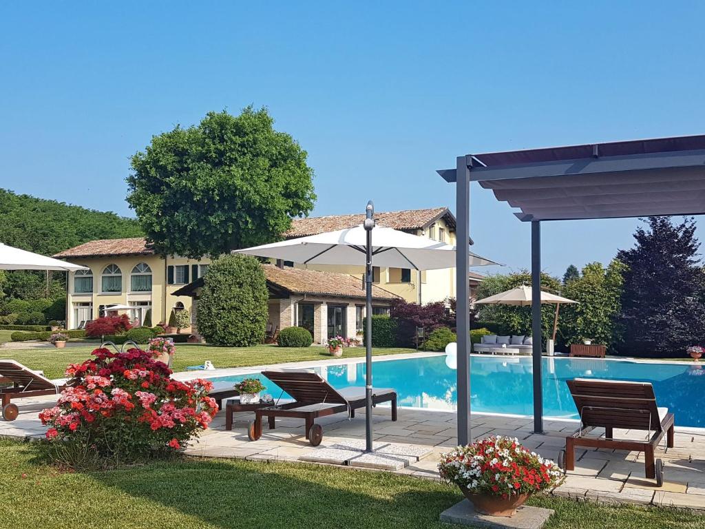 uma casa e uma piscina com bancos e guarda-sóis em Holiday Home Villa Carlotta by Interhome em Costigliole dʼAsti