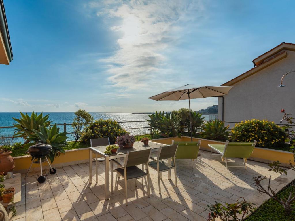 un patio con mesa, sillas y sombrilla en Holiday Home Terrazzo sul Mare by Interhome, en Cipressa