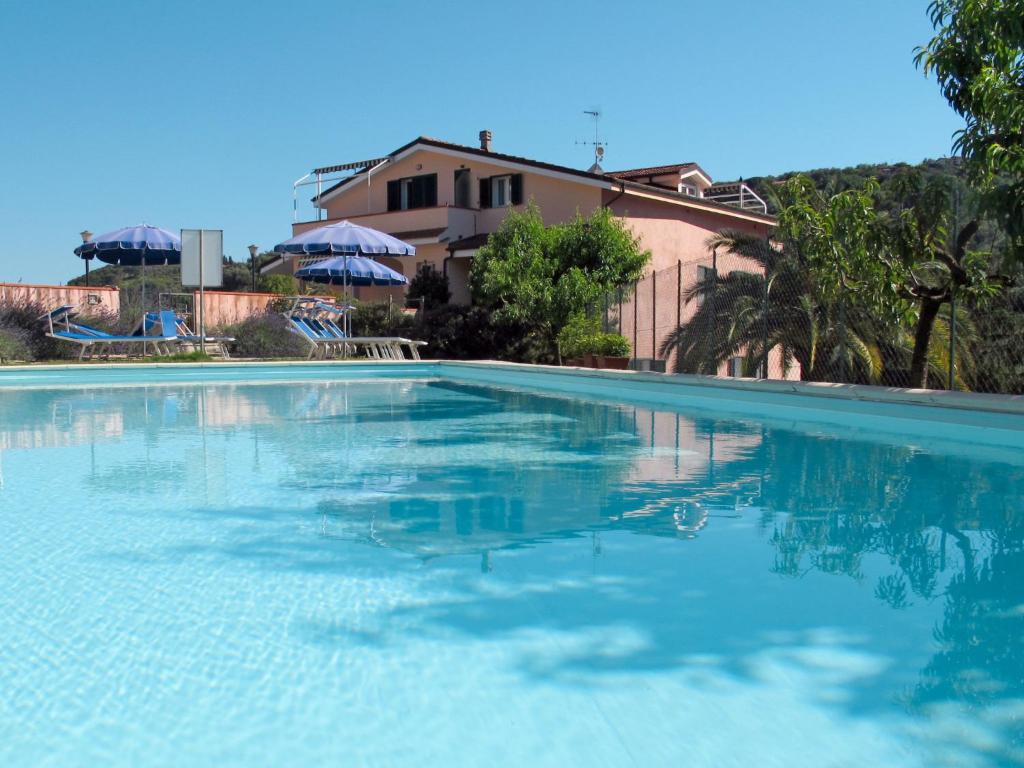 a large swimming pool with blue water in front of a house at Apartment La Colombera - DIA142 by Interhome in Diano Castello