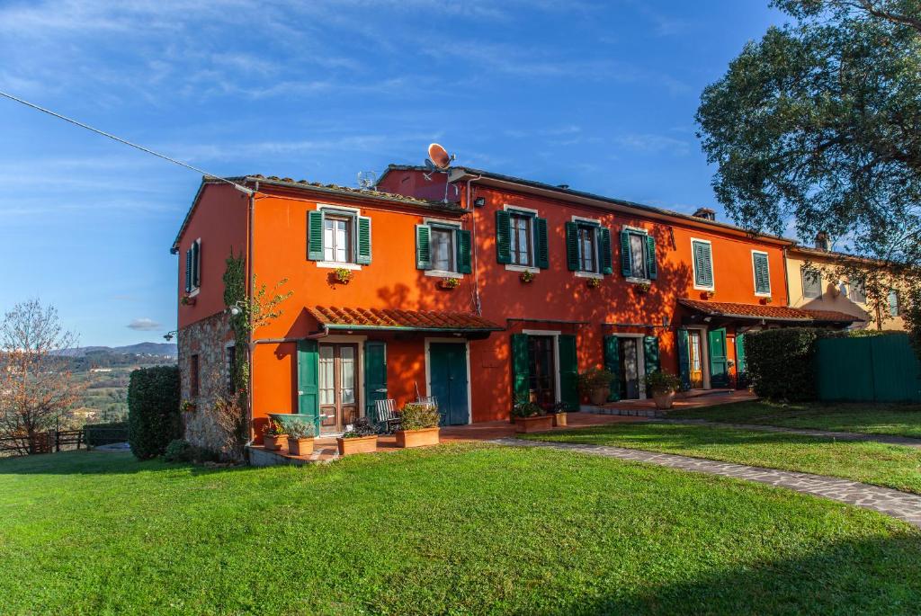 an orange house with a green lawn in front of it at Locanda agricola Posapiano in Montecarlo