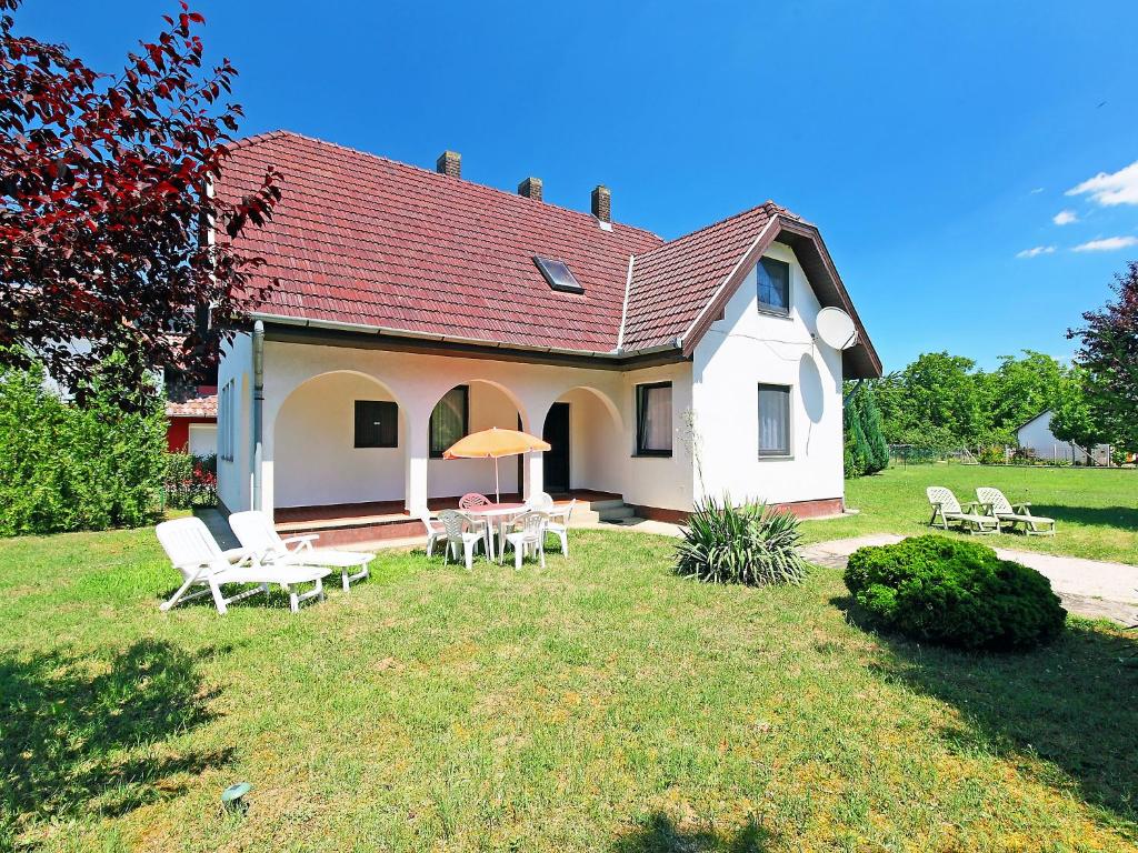 una casa blanca con sillas y mesas en un patio en Holiday Home Sunlight by Interhome, en Balatonőszöd