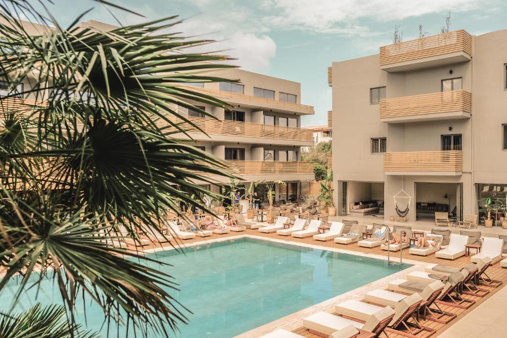 a swimming pool in front of a hotel with lounge chairs at Cook's Club Hersonissos Crete in Hersonissos