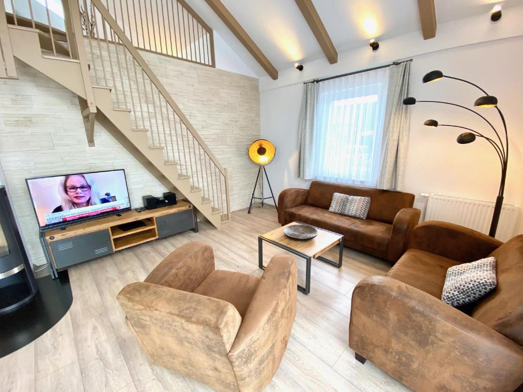 a living room with couches and a tv and stairs at mönchgut living & spa in Gager