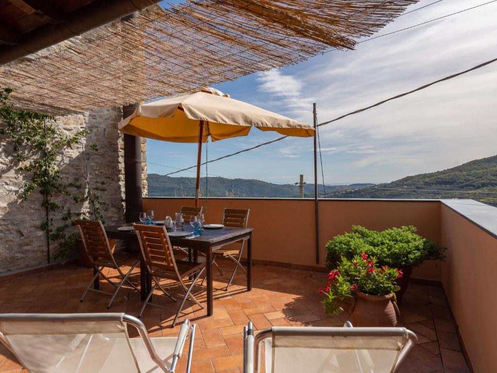 patio ze stołem, krzesłami i parasolem w obiekcie Holiday Home U Figu du Camin by Interhome w mieście Villa Viani