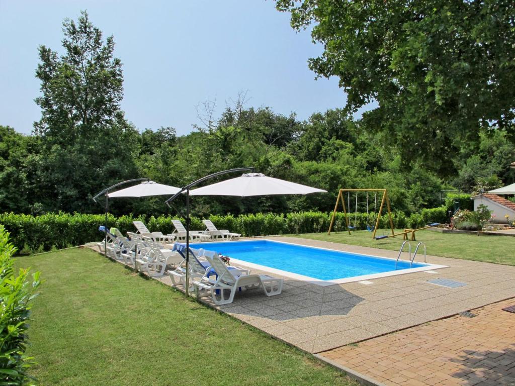 a pool with chairs and umbrellas in a yard at Apartment Radmila - MLK140 by Interhome in Gostinjac