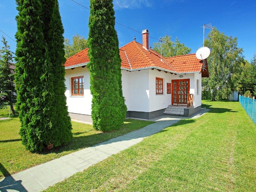 una casa blanca con techo rojo y dos árboles en Holiday Home Maria by Interhome en Balatonmáriafürdő