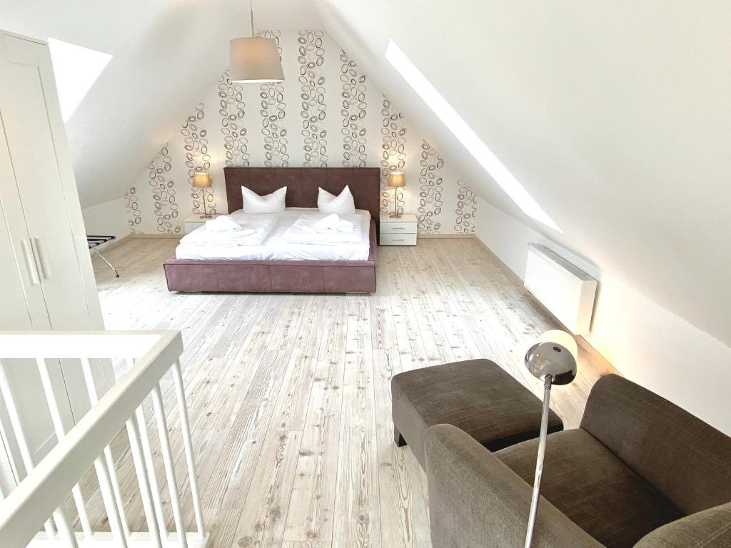 a bedroom with a bed and a couch and stairs at mönchgut living & spa in Gager