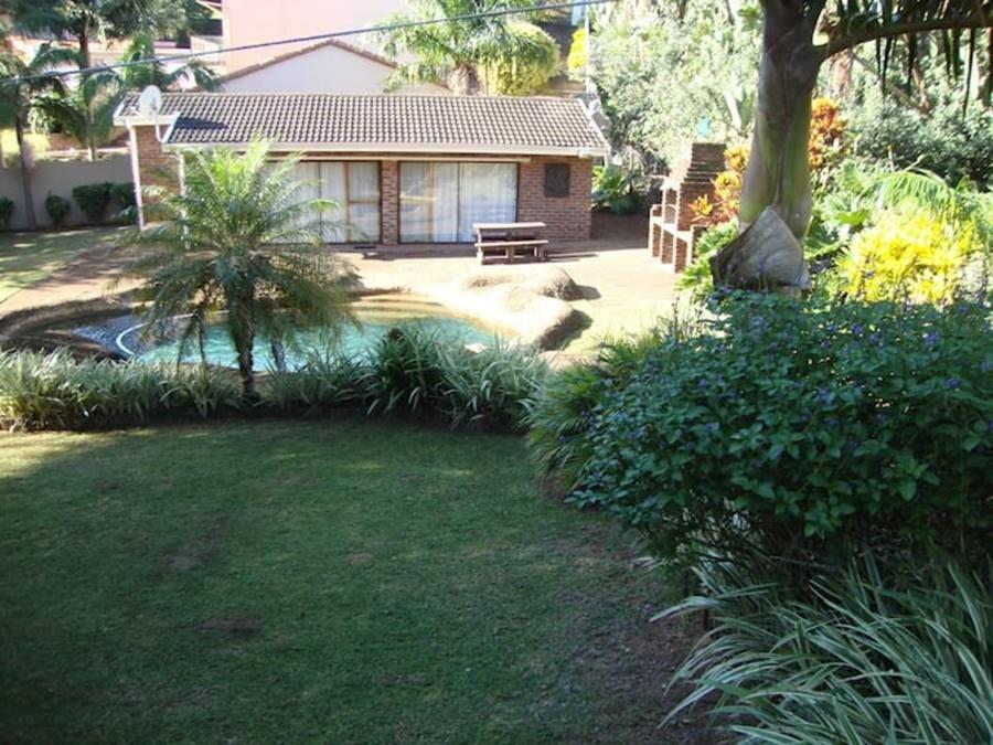 a garden with a bench in front of a house at Trafalgar Chalets Unit 1 in Southbroom