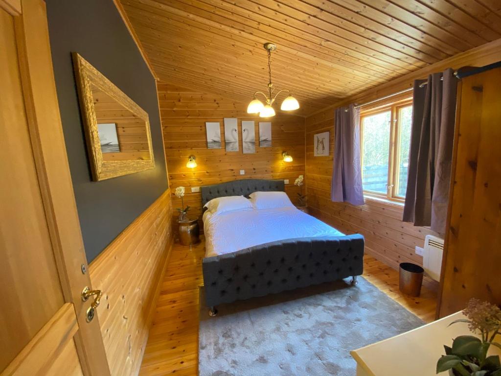 1 dormitorio con 1 cama en una habitación de madera en Owlet Lodge at Owlet Hideaway - with Hot Tub, Near York en Seaton Ross