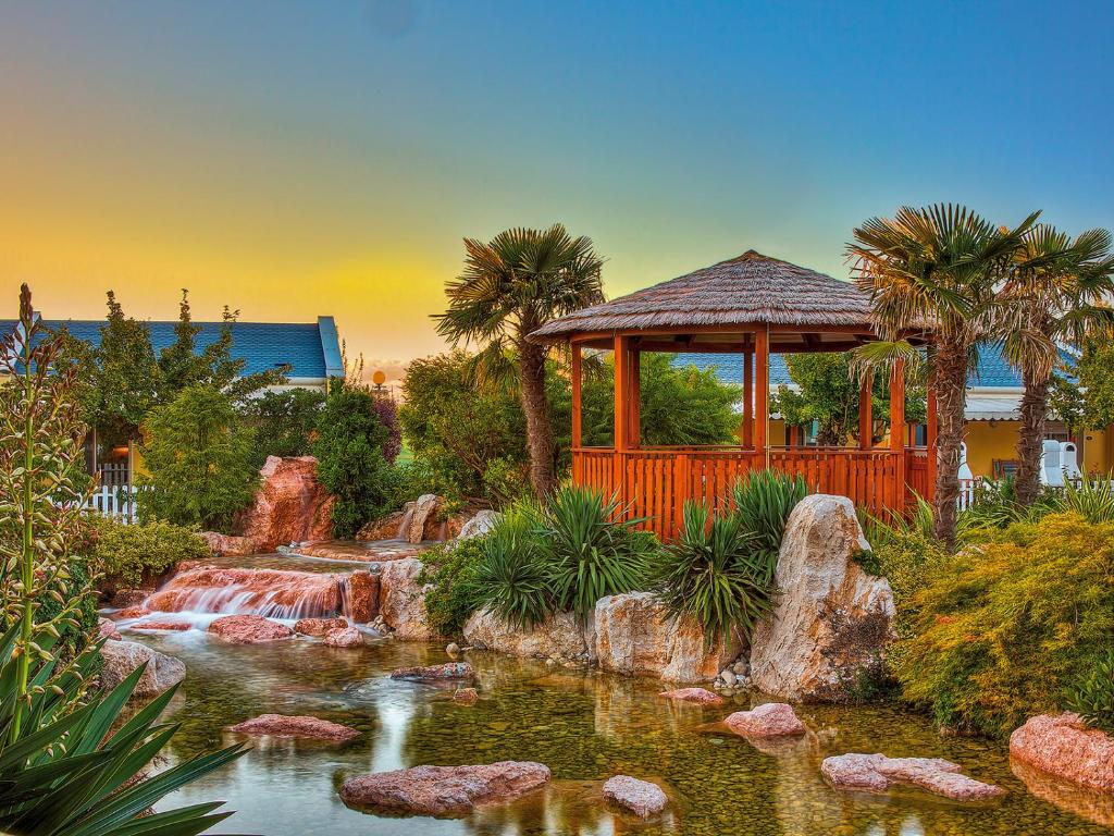 a garden with a pond and a gazebo at Portofelice Camping Village in Eraclea Mare