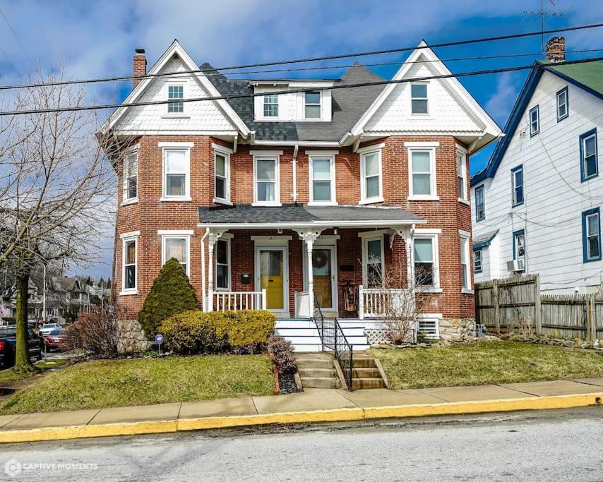 Quaint brick townhome in historic Kennett Square في ساحة كينيت: منزل من الطوب الأحمر مع باب أصفر