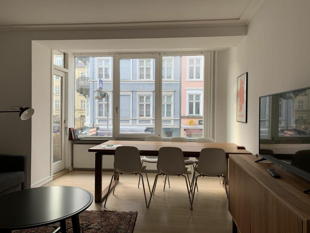 un soggiorno con tavolo, sedie e una grande finestra di ApartmentInCopenhagen Apartment 1423 a Copenaghen
