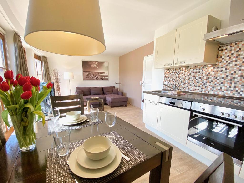 a kitchen and living room with a table with a vase of flowers at mönchgut living & spa in Gager