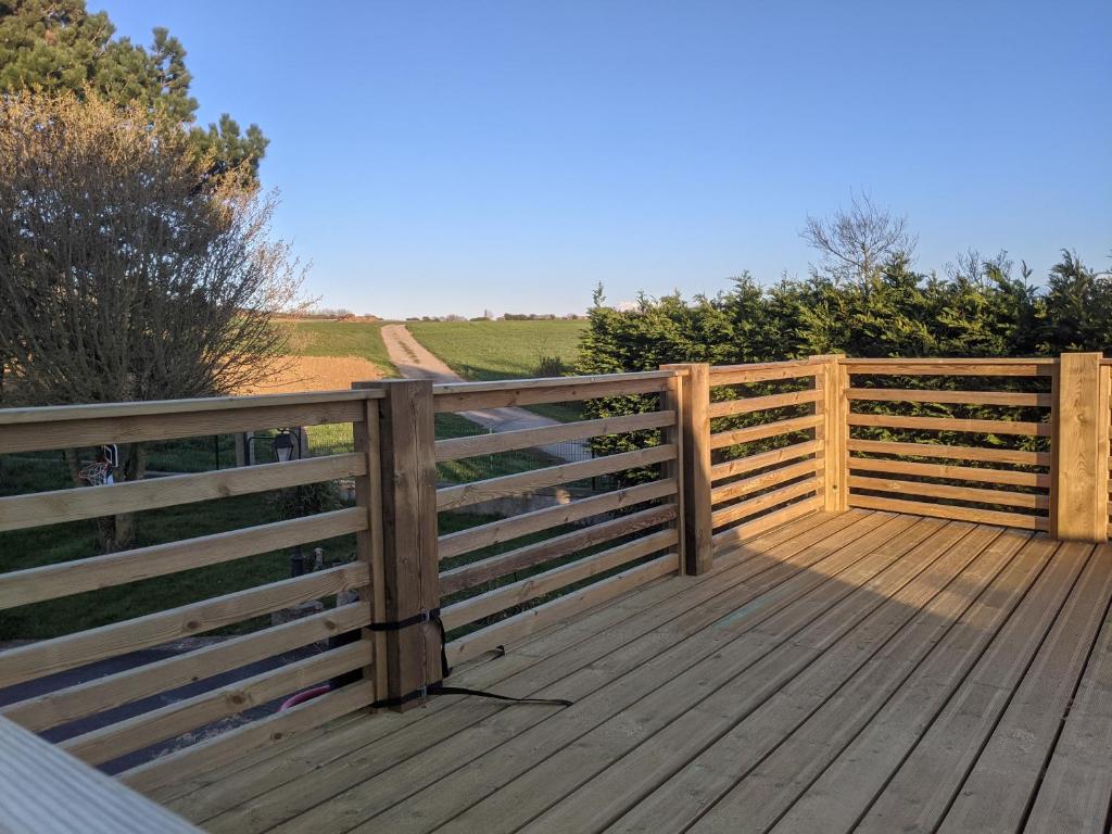 una terraza de madera con una valla lateral en Appartement - Au Vieux Moulin, en Leulinghen-Bernes