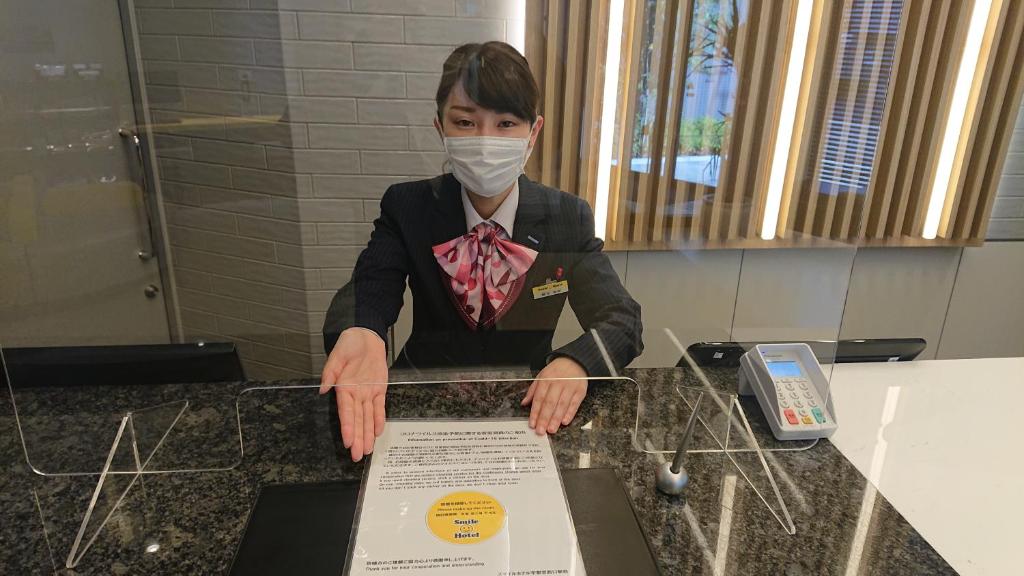 una persona con una máscara encima de un mostrador en Smile Hotel Namba, en Osaka