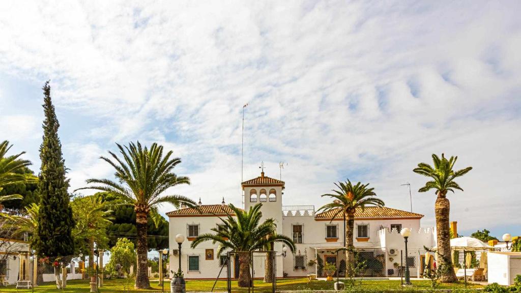 ein weißes Gebäude mit Palmen davor in der Unterkunft Hacienda El Corchuelo in Marchena
