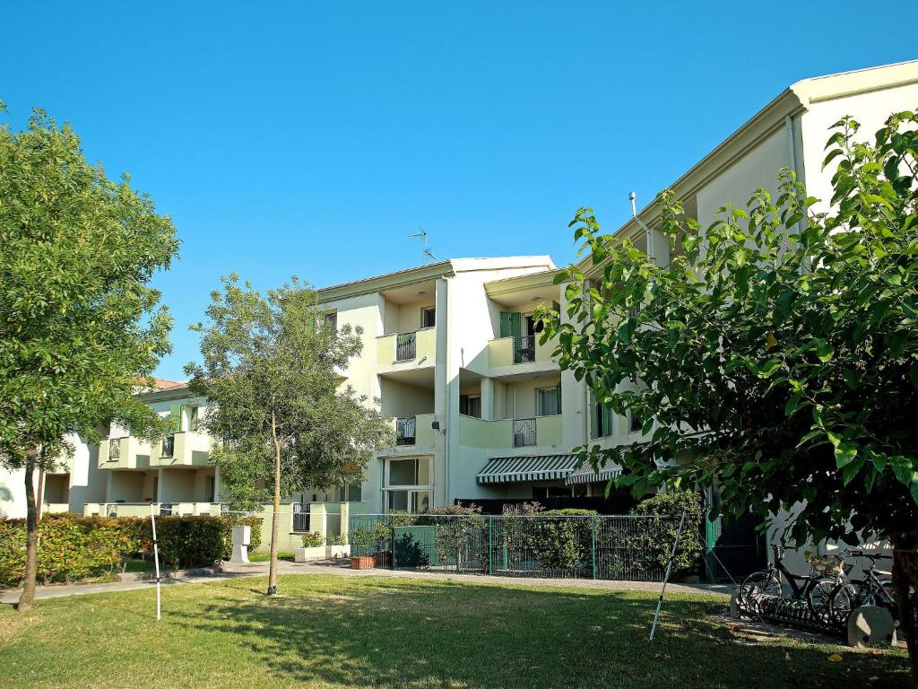 un edificio de apartamentos con árboles delante de él en Apartment Robinia-Pinetine-2 by Interhome, en Duna Verde