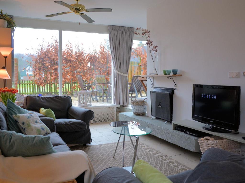 uma sala de estar com sofás e uma televisão de ecrã plano em Cosy Holiday Home in Noordwijkerhout near Lake em Noordwijkerhout