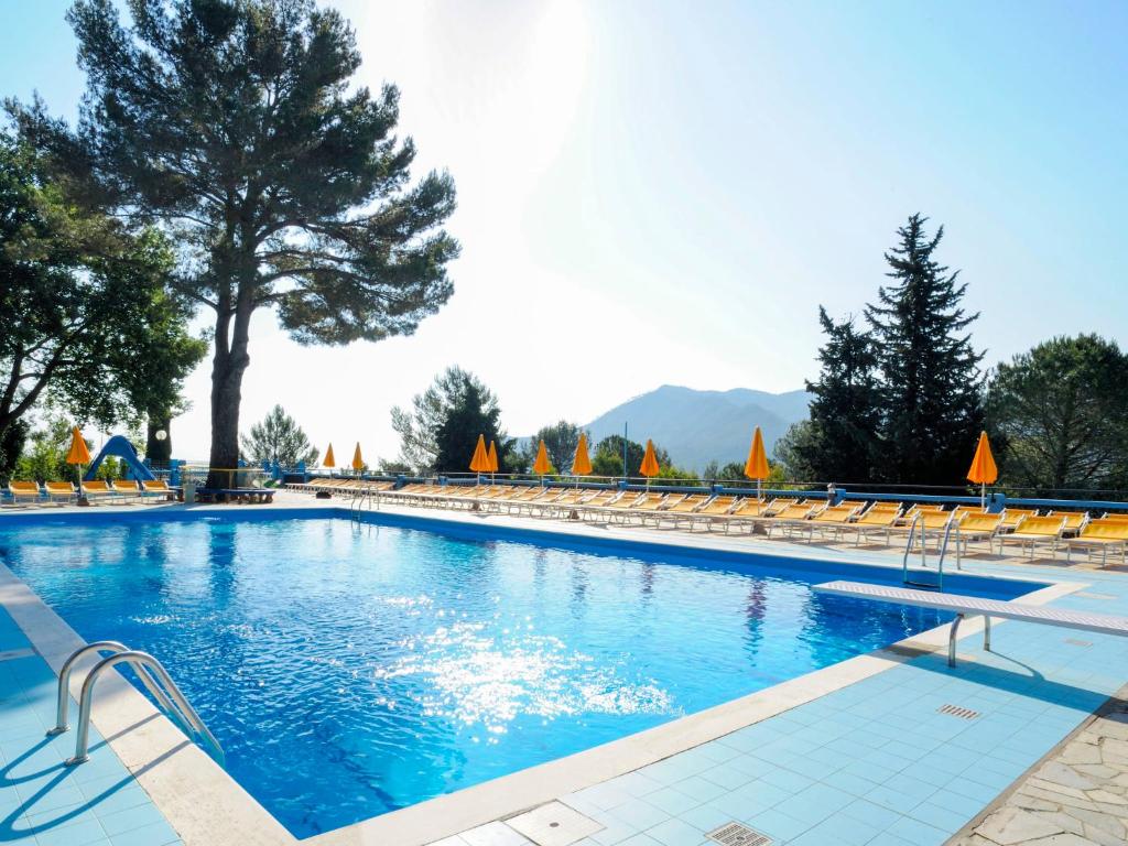 a large swimming pool with chairs and trees at Holiday Home Mobilhome B - AEG402 by Interhome in Villanova dʼAlbenga