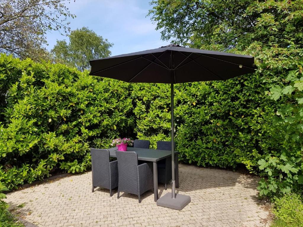 een tafel en stoelen onder een zwarte paraplu bij Charming Holiday Home in Garderen with Garden in Garderen