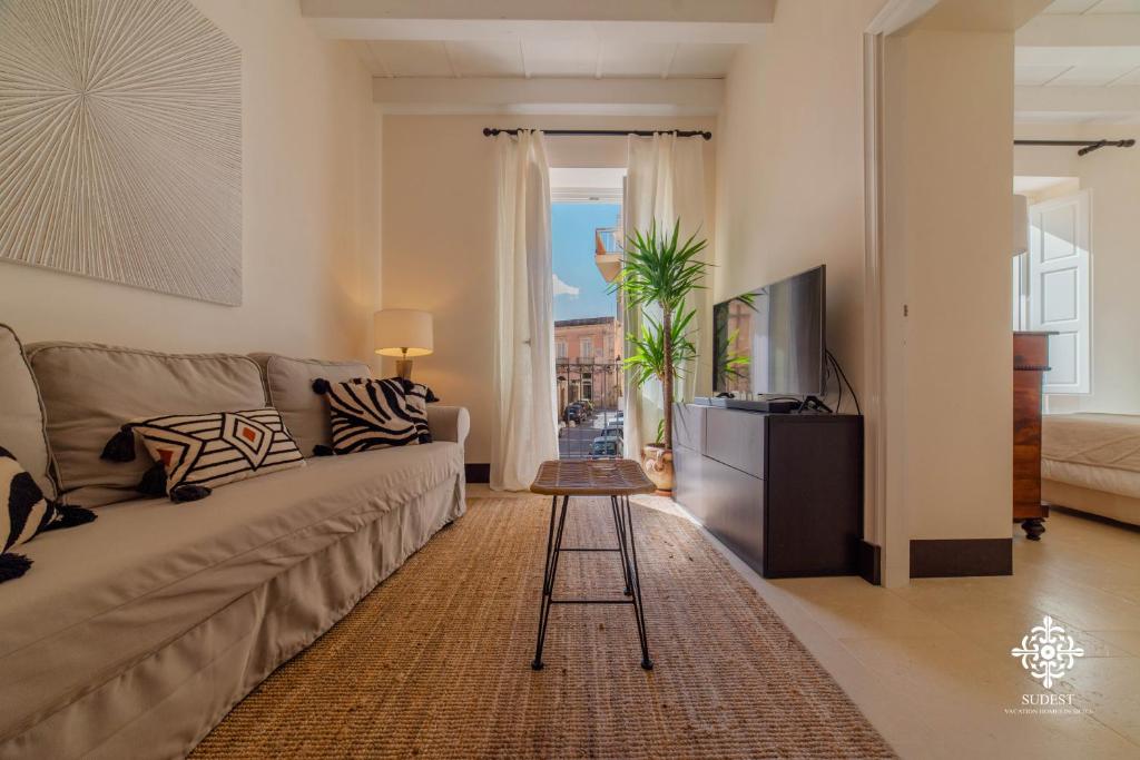 een woonkamer met een bank en een tv bij Casa Ramal - Tipica dimora Siciliana in Siracusa