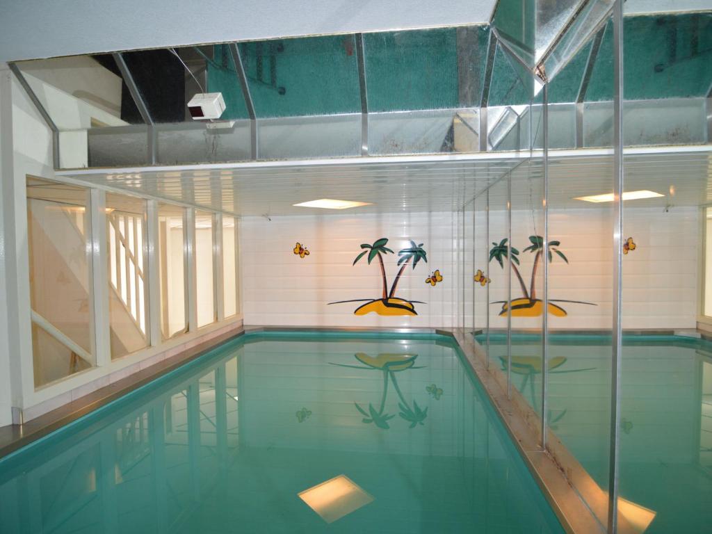 uma piscina com água azul e palmeiras na parede em Holiday home with pool sauna em Lunteren