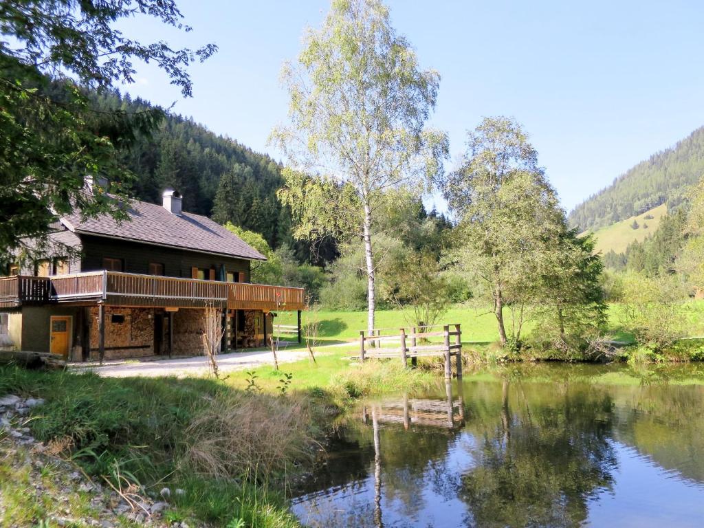 una cabaña de madera junto a un lago con una valla en Chalet Fischerhütte - STN100 by Interhome, en Sankt Nikolai im Sölktal