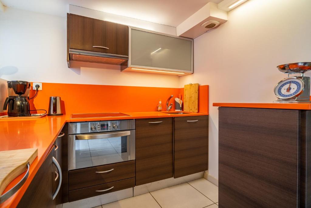a kitchen with brown cabinets and an orange wall at MAGNOLIAS 2- quartier résidentiel proche de la plage in Hendaye
