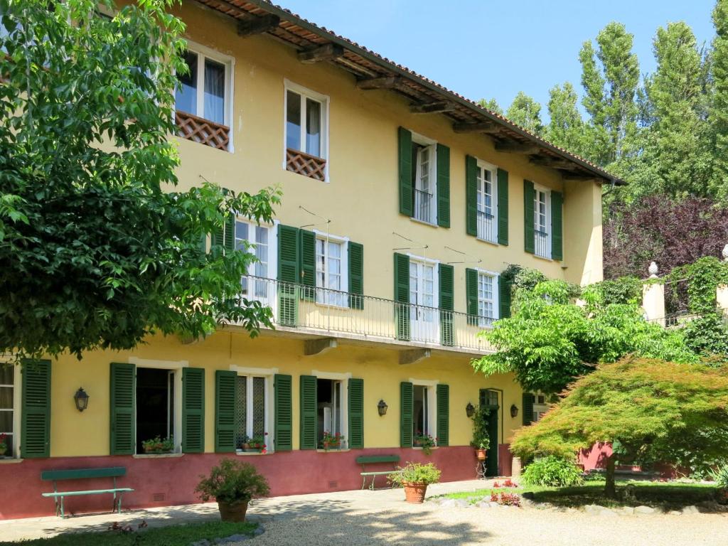 una casa antigua con persianas verdes y árboles en Apartment Appartamento del Castello by Interhome, en San Giorgio Canavese