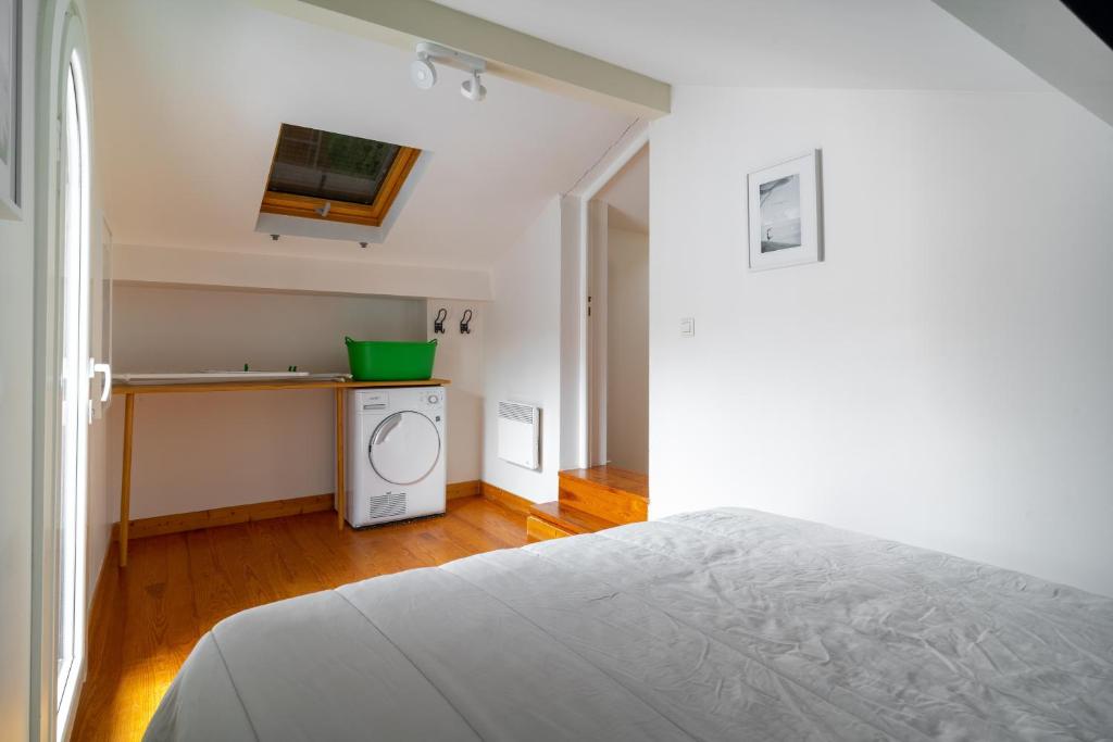 a bedroom with a white bed and a kitchen at MAGNOLIAS 2- quartier résidentiel proche de la plage in Hendaye