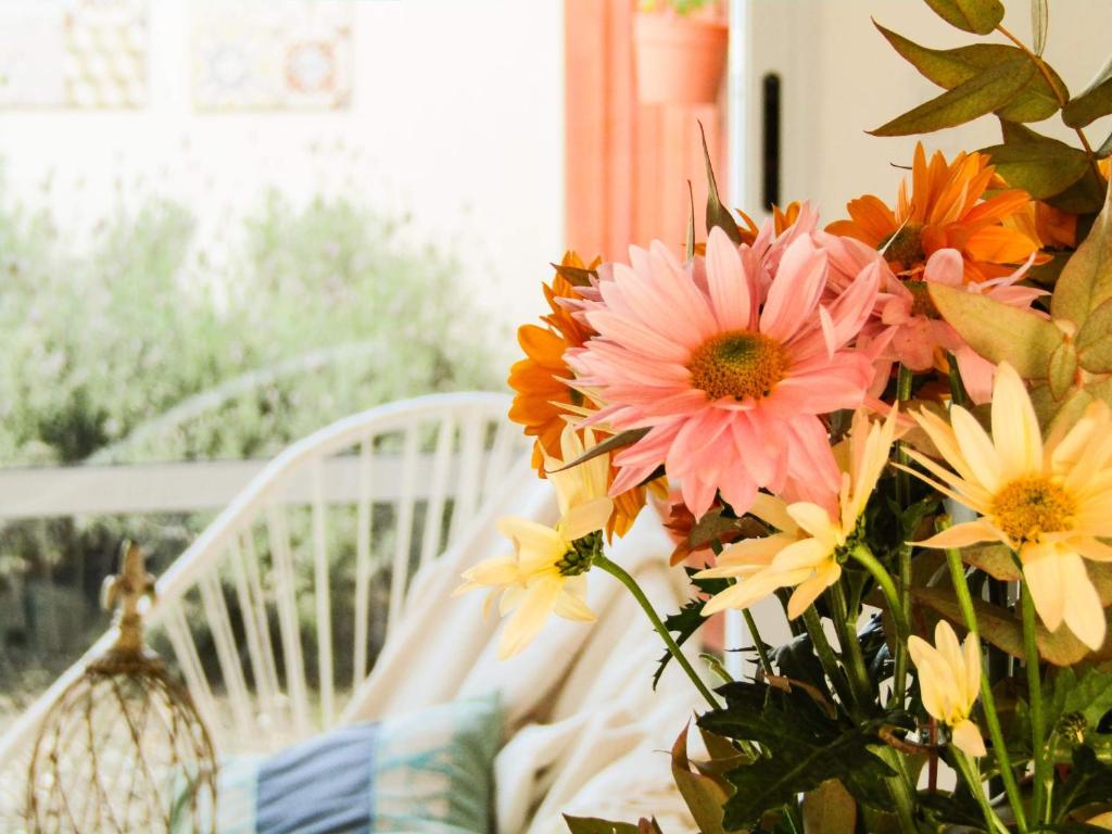 eine Vase voller Blumen neben einem weißen Stuhl in der Unterkunft Apartamento Duplex del Botanico in Villa Elisa