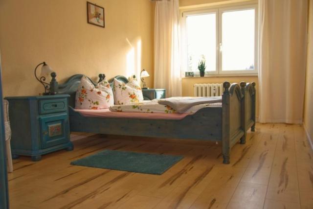 una camera con letto, finestra e pavimento in legno di Ferienwohnung Wolf a Gräfenroda