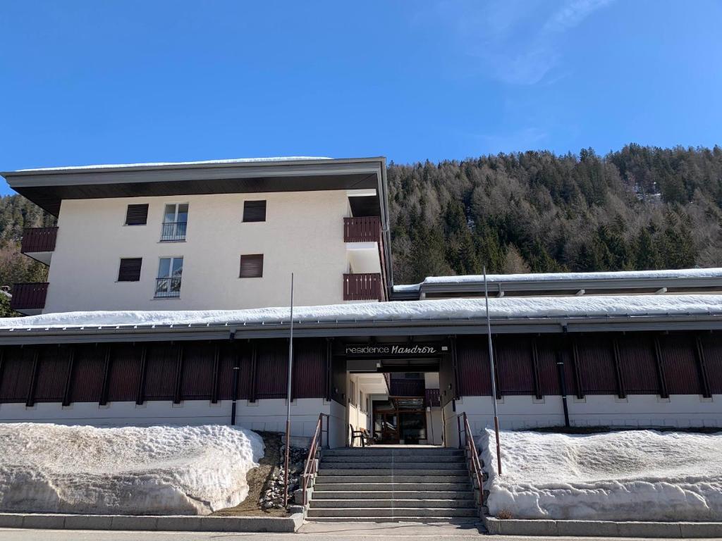 a building with snow on the stairs in front of it at Bilocale Mandron 105 in Madonna di Campiglio