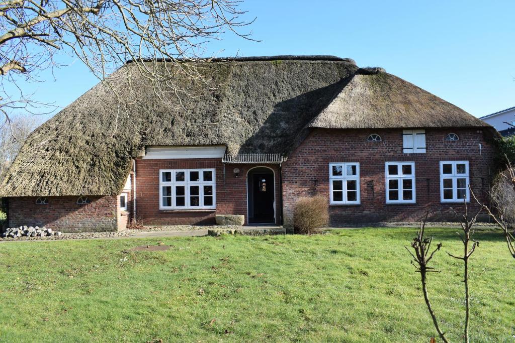 an old brick house with a thatched roof at Haus Amsel in Niebüll