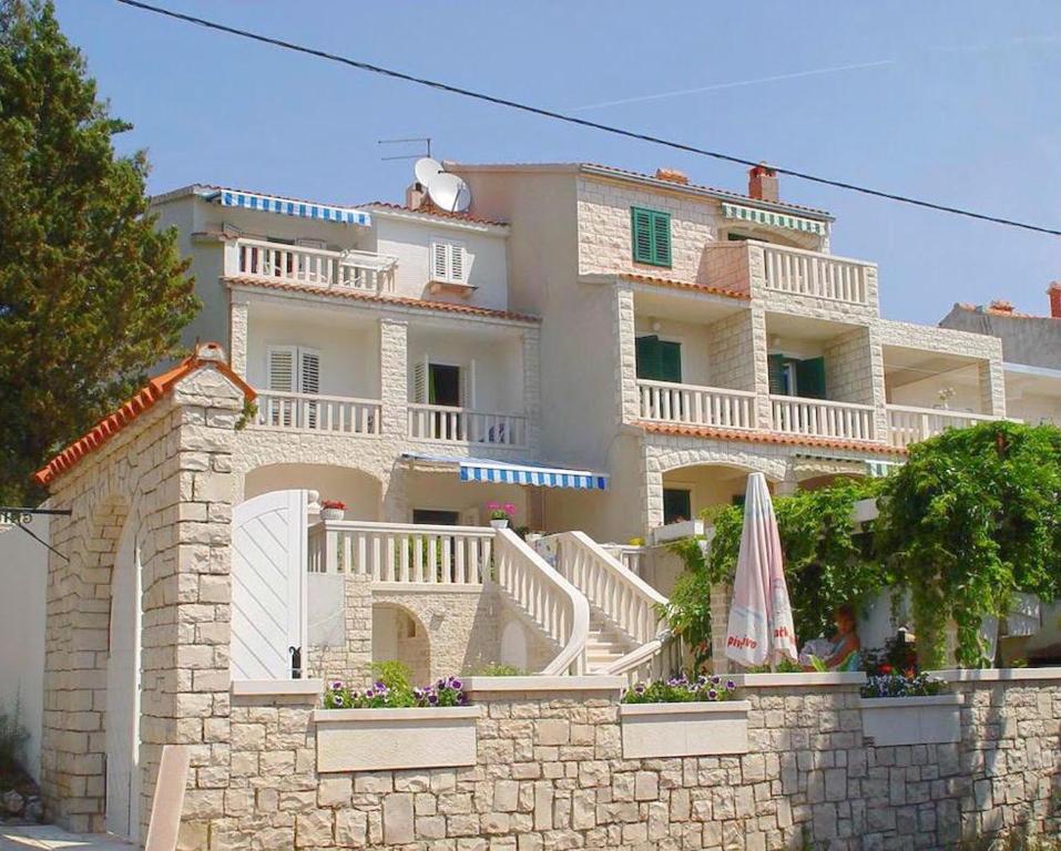 ein großes weißes Gebäude mit einem Balkon und einem Sonnenschirm in der Unterkunft Guest House Meri in Bol