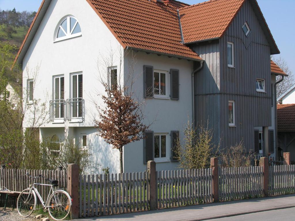 una casa blanca y negra con una valla y una bicicleta en Ferienwohnung Ruppert, en Euerdorf