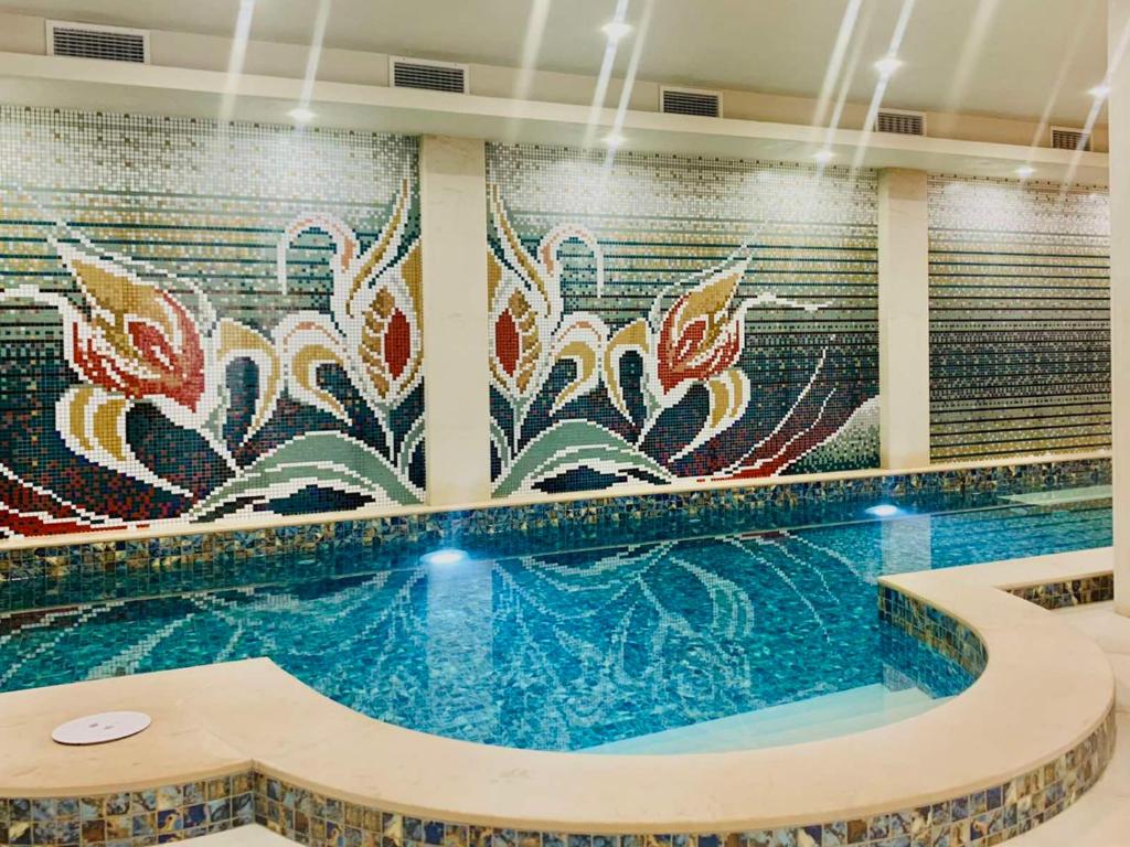 a swimming pool with a mosaic wall at ArdoSpa Hotel and Restaurant in Sarnitsa