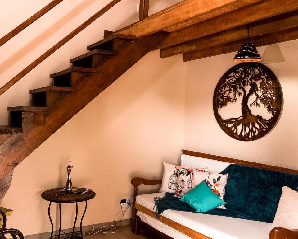 a living room with a couch with a tree on the wall at Capim Canoa in Alto Paraíso de Goiás
