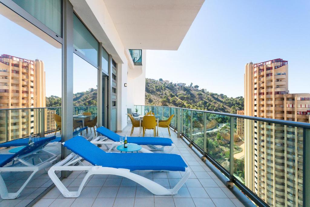 einen Balkon mit blauen Stühlen und einem Tisch in der Unterkunft Gran terraza privada con vistas espectaculares - Torre Lúgano in Benidorm