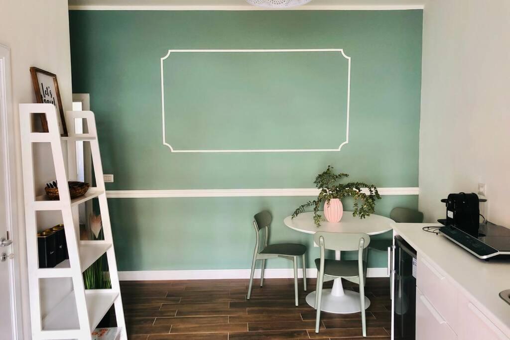 uma mesa e cadeiras num quarto com uma parede verde em La Casetta di Rosie, alla Torre Guevara em Potenza