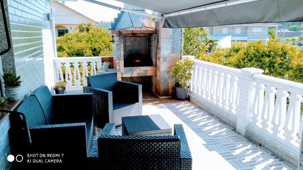 un patio con sillas y un balcón con chimenea en Perla, en Tui