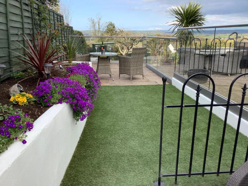 a balcony with a garden with purple flowers at Pendower Apartment in Wadebridge