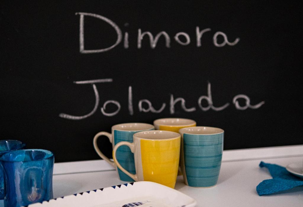 un grupo de tazas sentadas en una mesa con una pizarra en Dimora Jolanda, en Conversano