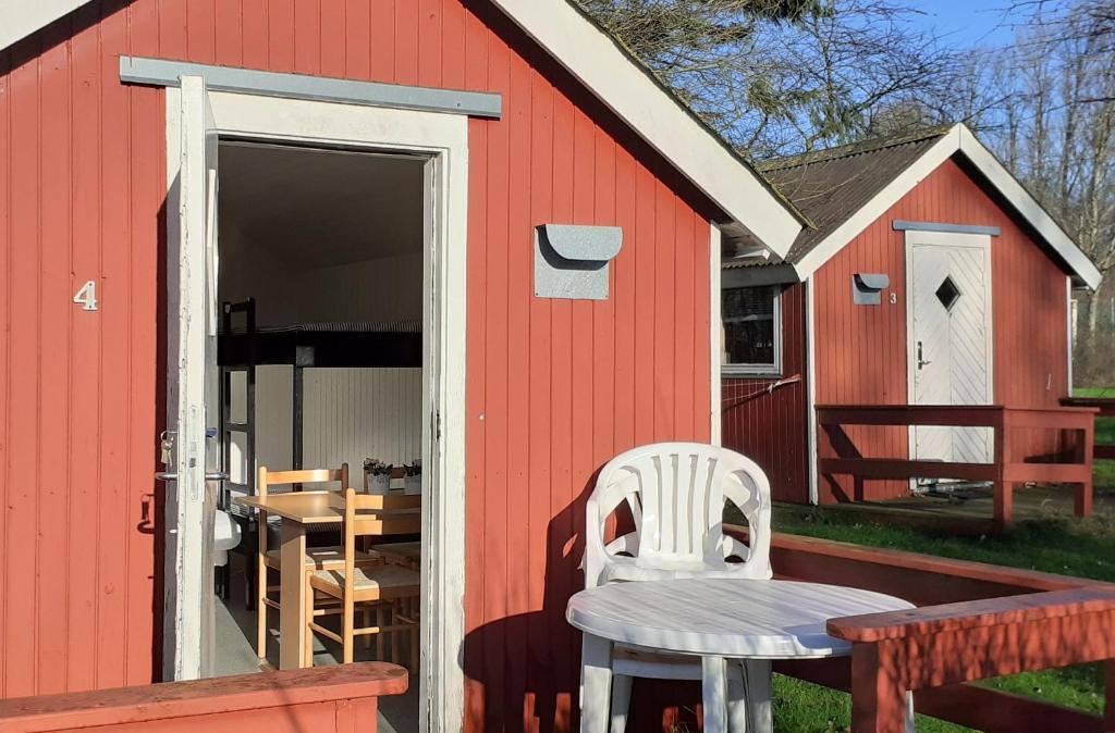 a red barn with a white chair and a table at Hytte - 1 rums hytter in Vig